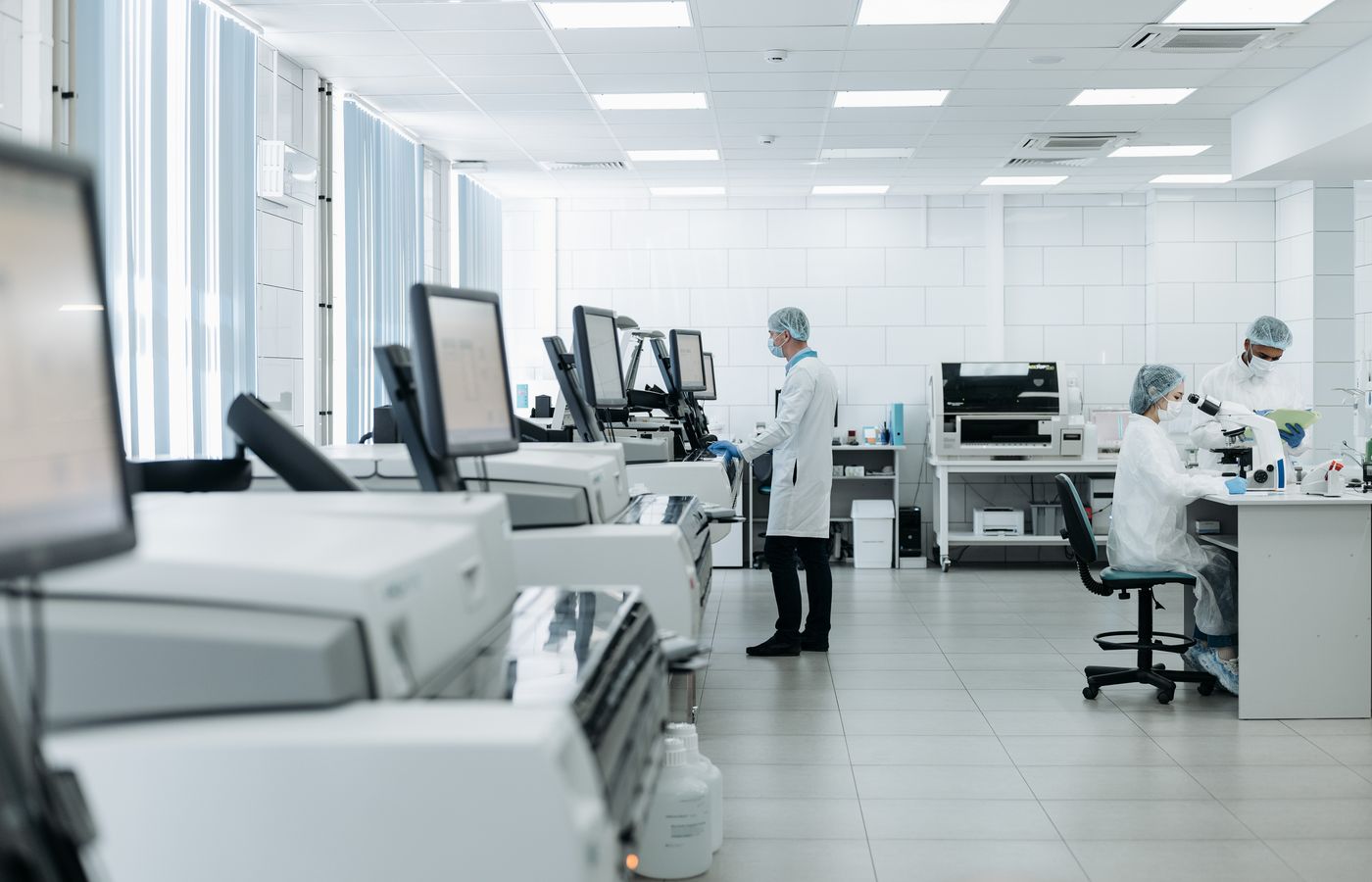 Profissionais trabalhando com equipamentos e computadores em um laboratório